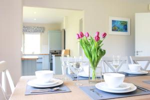 una mesa de comedor con tulipanes rosas en un jarrón en 4 bedroom holiday home with wheelchair accessible bathroom 2km from Kenmare en Kenmare