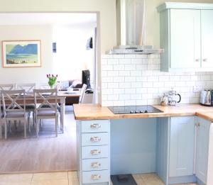 a kitchen with blue cabinets and a dining room at 4 bedroom holiday home with wheelchair accessible bathroom 2km from Kenmare in Kenmare