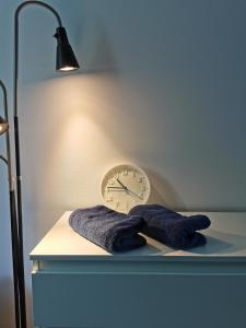 a clock and two towels on a table with a lamp at Comfortable apartment close to the center and sea in Gdańsk