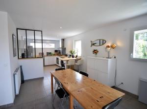 a kitchen and dining room with a wooden table at Marensines - Capbreton jolie villa mitoyenne sur grand jardinet et terrasse en bois in Capbreton +2 photos