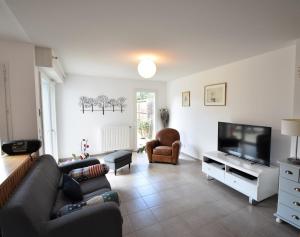 a living room with a couch and a flat screen tv at Marensines - Capbreton jolie villa mitoyenne sur grand jardinet et terrasse en bois in Capbreton