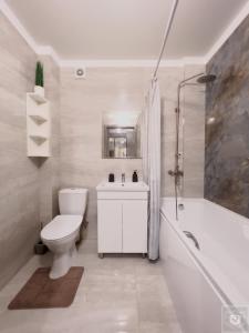 a bathroom with a toilet and a tub and a sink at RentHouse Apartments Urban Lion in Chişinău