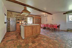 a kitchen with a refrigerator and a table with chairs at Le Moulin neuf in Alexain