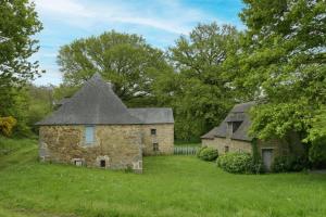 an old stone building with a gray roof in a field at Le Moulin neuf in Alexain
