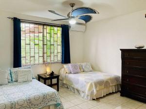 1 dormitorio con 2 camas, vestidor y ventana en La Mona Beach House, en Jacó