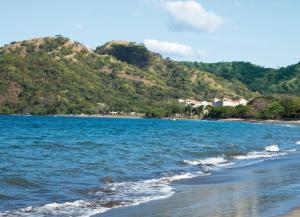 a view of a beach with mountains in the background at Riu Guanacaste - All Inclusive in Coco