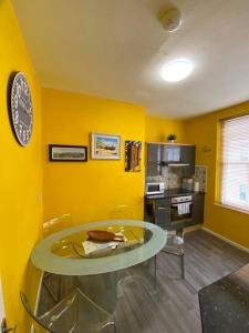 une salle à manger avec une table et un mur jaune dans l'établissement Apartment in Old Town near the beach, à Hastings