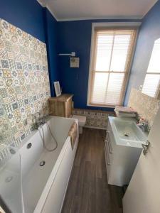 un bagno blu con vasca, lavandino e vasca di Apartment in Old Town near the beach a Hastings