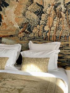 - un lit avec des oreillers blancs devant une tapisserie dans l'établissement Le Prieuré sur Seine, à Marnay-sur-Seine