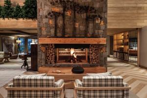 a fireplace in a living room with two chairs and a table at Hotel Alpestre in Gramado