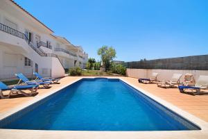 a swimming pool with lounge chairs and a house at Algarve apartments L in Olhos de Água