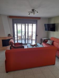 uma sala de estar com um sofá vermelho e cadeiras em Dominikis appartment em Nea Peramos
