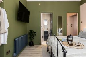 a bedroom with green walls and a bed and a tub at Stylish Central Apartment in Bournemouth