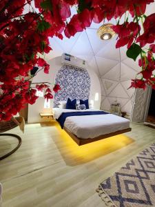 a bedroom with a bed in a room with red flowers at Bubbles Domes Private Cmp in Al Wāşil