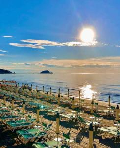 una spiaggia con sedie e ombrelloni e l'oceano di Hostdomus - Casa Corallo ad Alassio