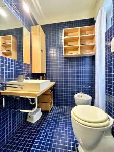 Baño de azulejos azules con aseo y lavamanos en Hostdomus - Casa Corallo, en Alassio