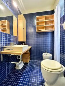 un bagno piastrellato blu con un water e un lavandino di Hostdomus - Casa Corallo ad Alassio Altre 33 foto