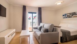 a bedroom with a couch and a bed and a window at ILUNION Costa Sal Lanzarote in Puerto del Carmen