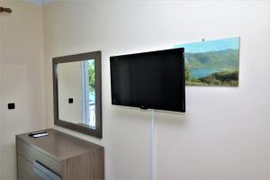 telewizor z płaskim ekranem wiszący na ścianie obok lustra w obiekcie Marianna Appartaments w mieście Plataria