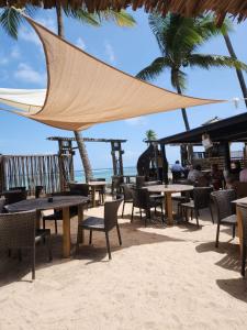 ein Restaurant am Strand mit Tischen und Stühlen in der Unterkunft Le NIL in Sainte-Anne