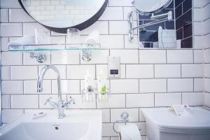 La salle de bains est pourvue de carrelage blanc, d'un lavabo et de toilettes. dans l'établissement Hotel Indigo - Bath, an IHG Hotel, à Bath