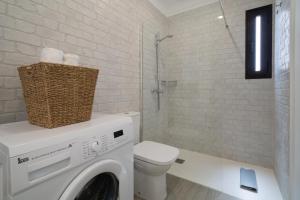 Un baño con lavadora y un inodoro. en Sabbia Suites My Place, en La Santa 1 foto más