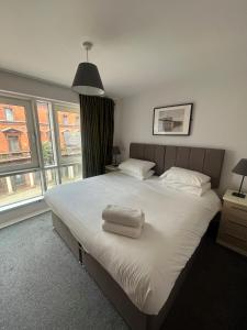 a bedroom with a large bed with two towels on it at Quayside Apartments in Cardiff