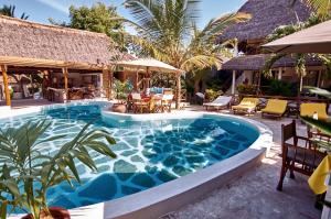 a swimming pool in a resort with tables and chairs at Mvuvi Fishing Lodge in Watamu