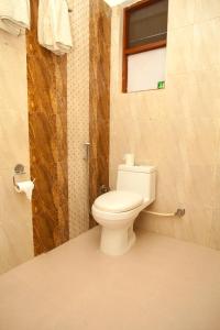 La salle de bains est pourvue de toilettes blanches et d'une fenêtre. dans l'établissement Sauraha Holiday Home Riverside, à Chitwan