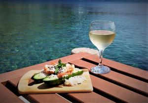 a glass of wine and a plate of sushi and a glass of white wine at Symi . VILLA CALME (Sur la Mer). in Symi