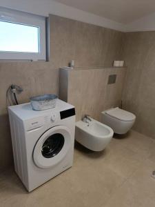 a bathroom with a washing machine and a toilet at House in Istria in Plomin