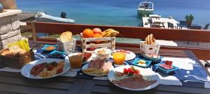 a table with breakfast food on a table with a view of the ocean at Symi . VILLA CALME (Sur la Mer). in Symi
