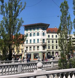 a white building with a fence in front of it at Triple Bridge Ljubljana in Ljubljana