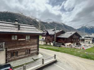 un grupo de edificios de madera con montañas en el fondo en Fior d'Alpe Apartment en Livigno