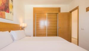 a bedroom with a white bed and a wooden door at ILUNION Costa Sal Lanzarote in Puerto del Carmen