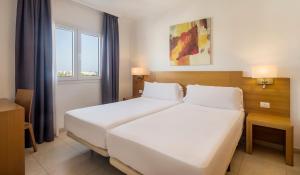a bedroom with a large white bed and two windows at ILUNION Costa Sal Lanzarote in Puerto del Carmen