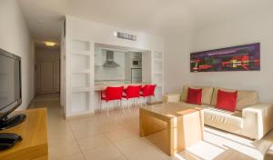 a living room with a couch and a table and red chairs at ILUNION Costa Sal Lanzarote in Puerto del Carmen