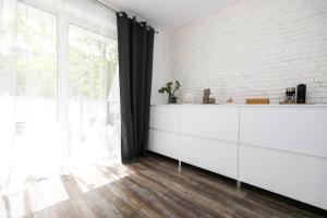 a kitchen with white cabinets and a brick wall at ALURE RESIDENCES 1 & 24h self check-in in Banská Bystrica