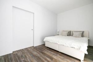 biała sypialnia z białym łóżkiem i drewnianą podłogą w obiekcie ALURE RESIDENCES 1 & 24h self check-in w Bańskiej Bystrzycy