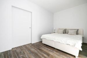 a white bedroom with a white bed and wooden floors at ALURE RESIDENCES 1 & 24h self check-in, free parking in front of the apartment building, new building, terrace, cafe with breakfast in the apartment building, next to the aqua park in Banská Bystrica +24 photos