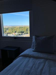 a bedroom with a bed and a large window at MI CASA TU CASA in El Calafate