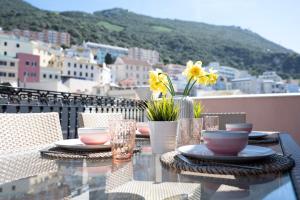 een tafel met borden, kopjes en bloemen op een balkon bij Luxurious Penthouse Studio with Private Terrace - Grand Central House in Gibraltar