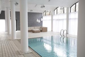 a room with a pool with a couch and a chair at Comwell Kolding in Kolding