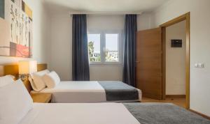 a hotel room with two beds and a window at ILUNION Costa Sal Lanzarote in Puerto del Carmen