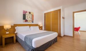 a bedroom with a large bed and a red chair at ILUNION Costa Sal Lanzarote in Puerto del Carmen