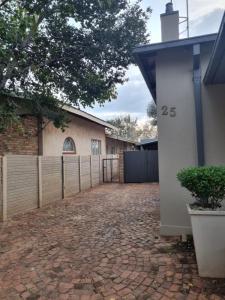 a driveway in front of a house with a fence at Riebeeck Cottage in Potchefstroom