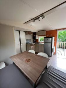 eine Küche und ein Esszimmer mit einem Holztisch und Stühlen in der Unterkunft Mobil Home Cosi pour 6 (Camping Tohapi) in Vogelgrun