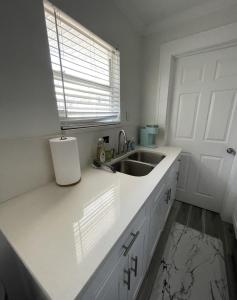 a white kitchen with a sink and a window at The Blue Wave Suite Unit B in St Petersburg