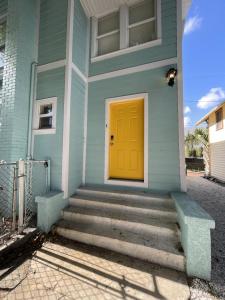 a blue house with a yellow door and stairs at The Blue Wave Suite Unit C in St Petersburg