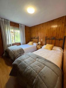 Habitación con 2 camas y paredes revestidas de madera. en Casa en Treceño 5 Dormitorios y 2 Plantas, en Treceño